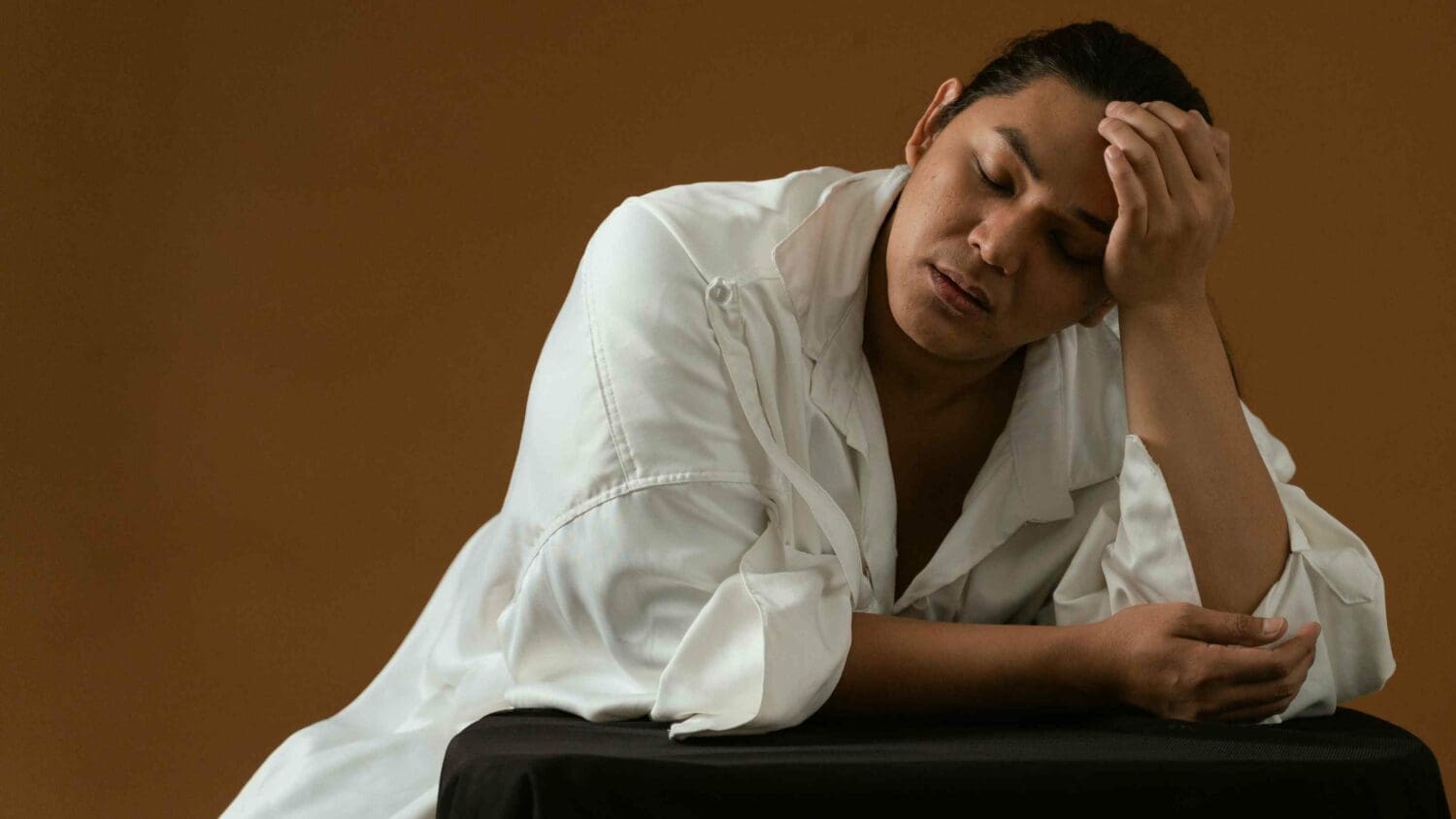 Man with head in his hand, starting to conenct with his own needs and stop people-pleasing